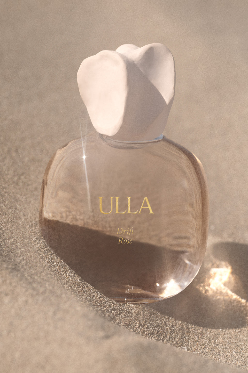 ULLA Drift Rose Designer Perfume Bottle Resting on Sun-Warmed Sand - Lifestyle | Ulla Johnson